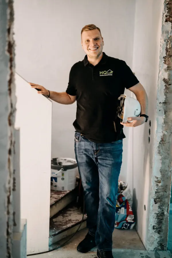 Andre Handschuh von HQ Energieberatung mit Bauhelm und Wasserwaage auf einem Sanierungsprojekt