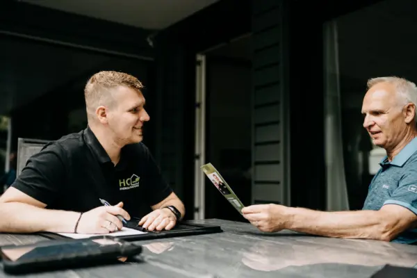 Andre Handschuh von HQ Energieberatung im persönlichen Erstgespräch mit einem Kunden auf der Terrasse – Kunde hält HQ-Informationsflyer